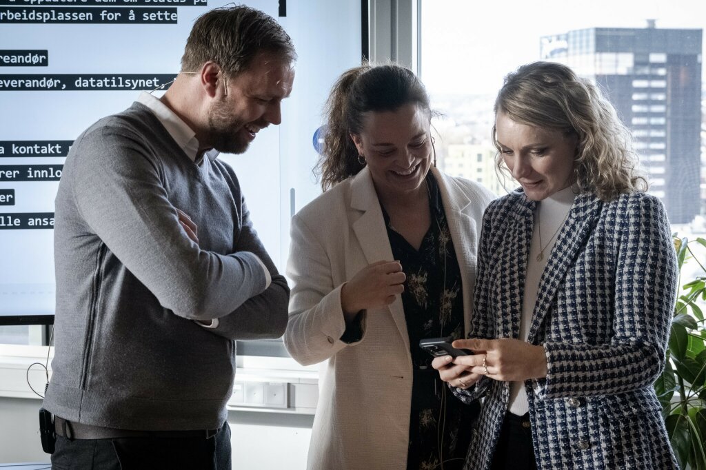 Our founder, Erlend, and two colleagues looking at a mobile phone during a cybersecurity exercise.